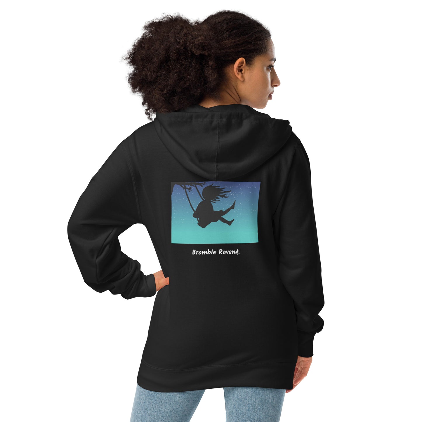 Original Swing Free design of a girl's silhouette in a tree swing against the backdrop of a blue starry sky. Rectangular image on the back of a unisex fleece-lined black colored zip up hoodie. Shown on female model.