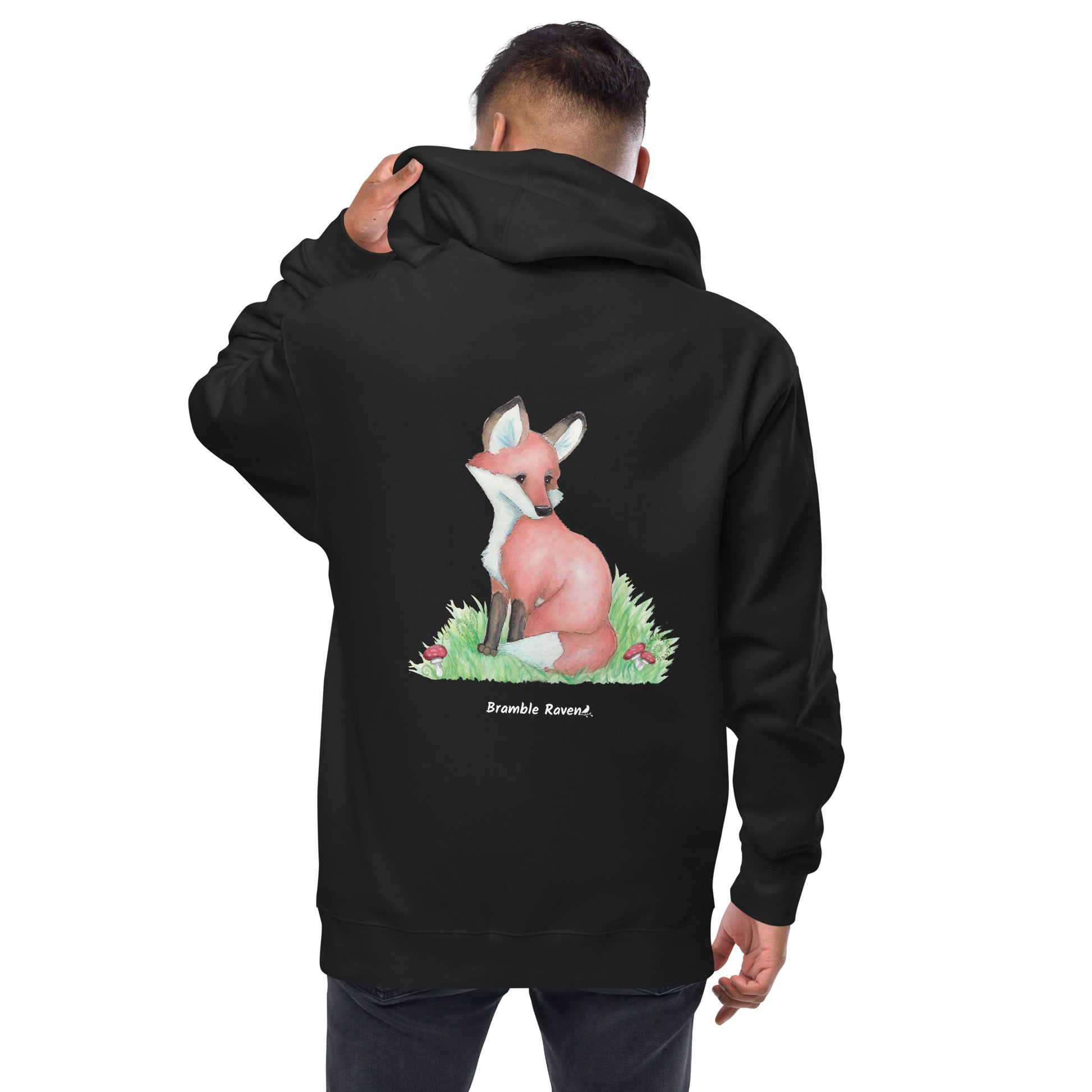 Black colored unisex fleece zip up hoodie. Back design features a watercolor fox in the grass with ferns and mushrooms. Has a jersey-lined hood, metal eyelets and zipper. Back view shown on male model.