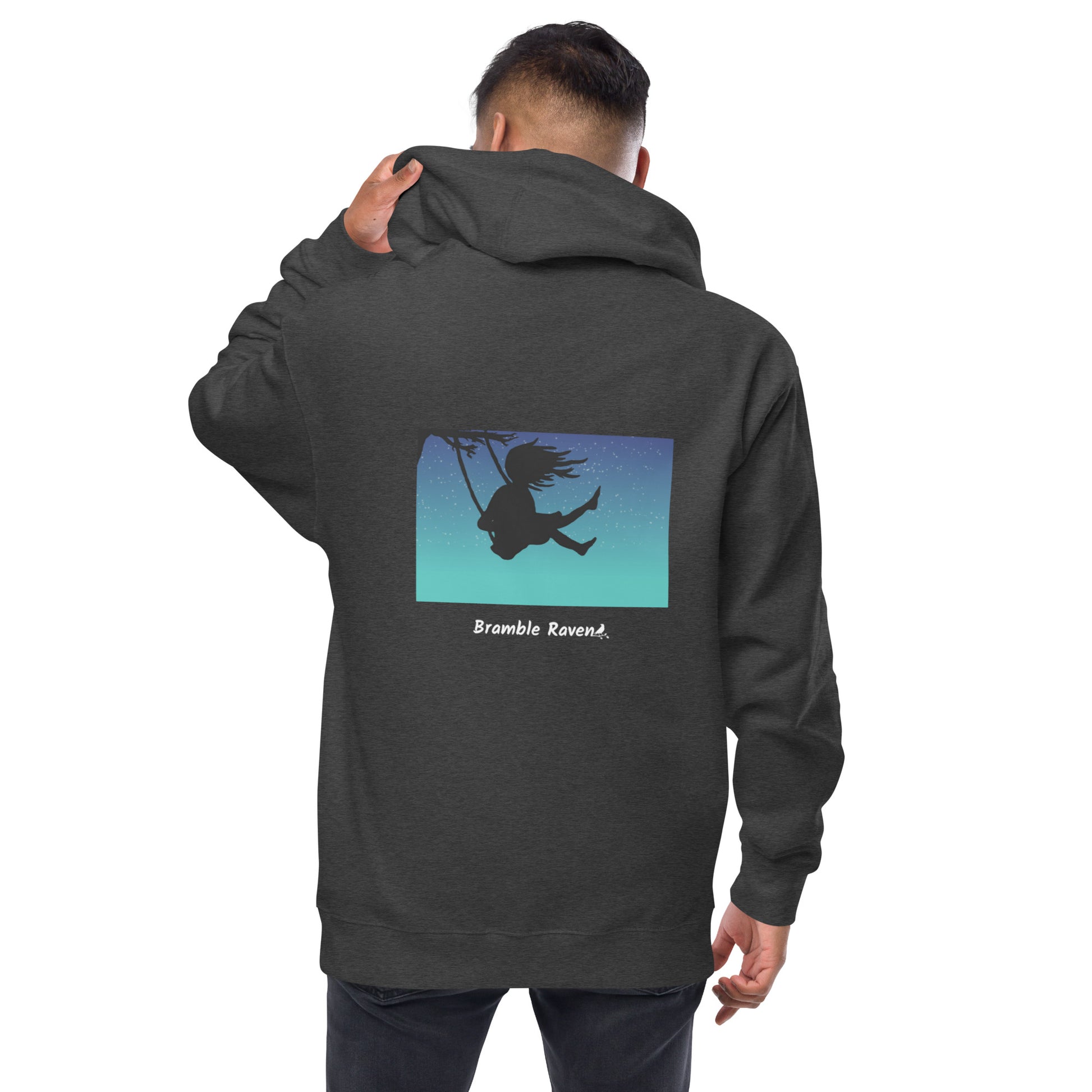 Original Swing Free design of a girl's silhouette in a tree swing against the backdrop of a blue starry sky. Rectangular image on the back of a unisex fleece-lined charcoal heather grey colored zip up hoodie. Shown on male model.