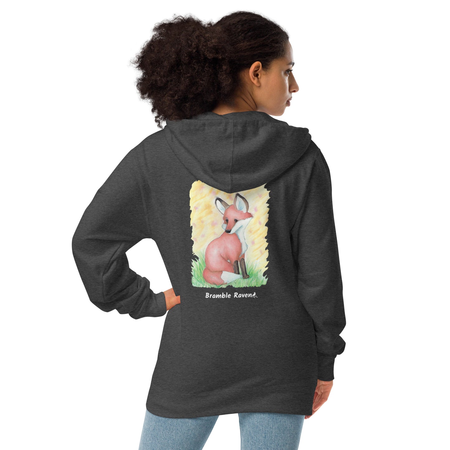 Unisex charcoal heather grey colored zip-up fleece-lined hoodie. Features original watercolor painting of a fox sitting in the grass on the back of the hoodie. Shown on female model.