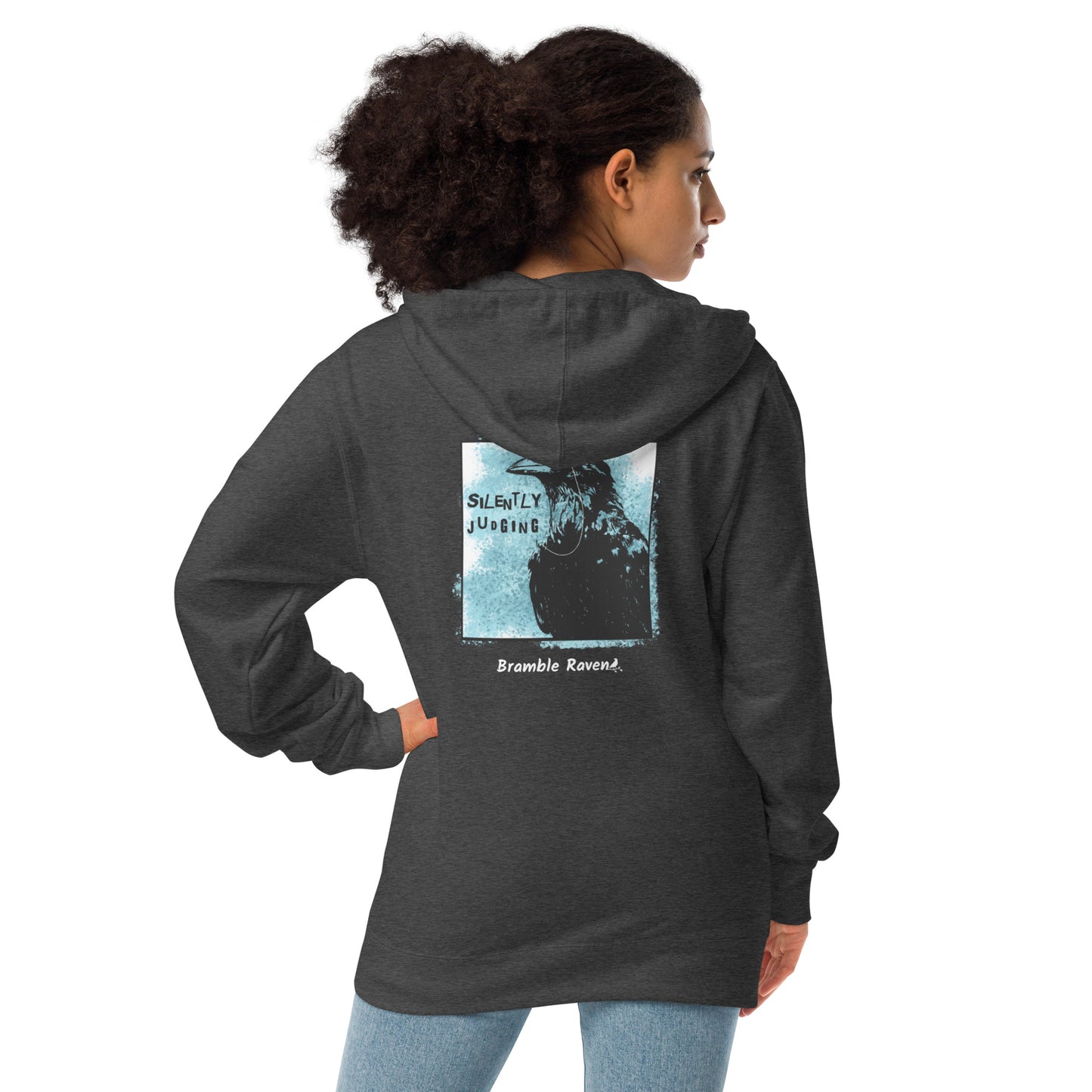Unisex fleece-lined charcoal heather grey colored zip-up hoodie with silently judging text by black crow wearing a monocle in a square with blue paint splatters.  Design on the back of hoodie. Shown on female model.