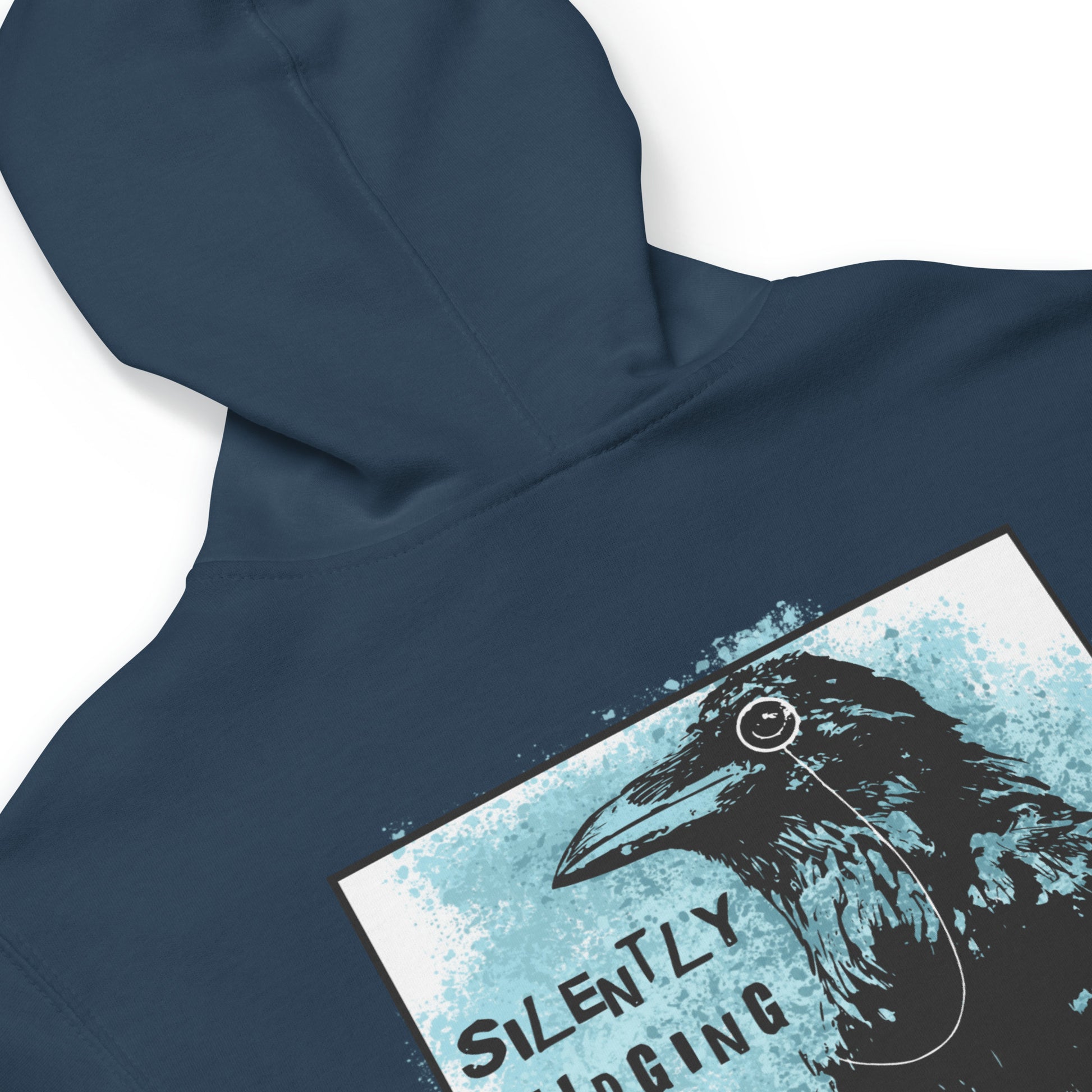 Unisex fleece-lined navy blue colored zip-up hoodie with silently judging text by black crow wearing a monocle in a square with blue paint splatters.  Design on the back of hoodie. Image shows detail of hood seam.