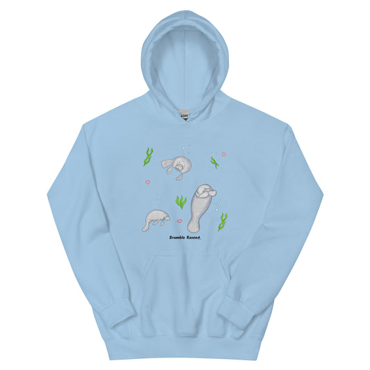 Light blue colored unisex hoodie. 50% cotton 50% polyester. Features a design of three manatees surrounded by seaweed, seashells, and bubbles. Has a double lined hood, ribbed cuffs, and a front pouch pocket.
