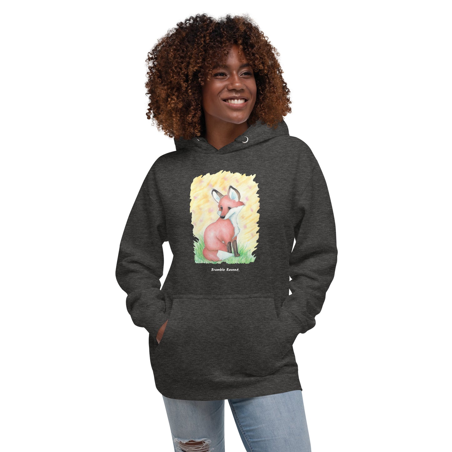 Unisex charcoal heather grey colored hoodie. Features original watercolor painting of a fox in the grass against a yellow backdrop. Shown on female model.