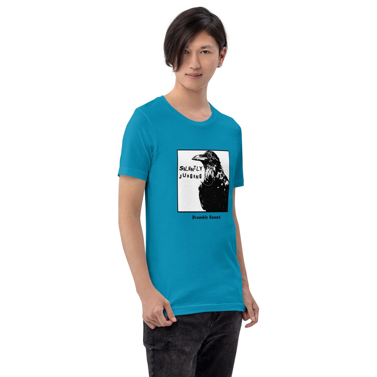 Unisex aqua colored t-shirt. Features silently judging text next to black crow wearing a monocle in a square frame on a white background.  Shown on male model.