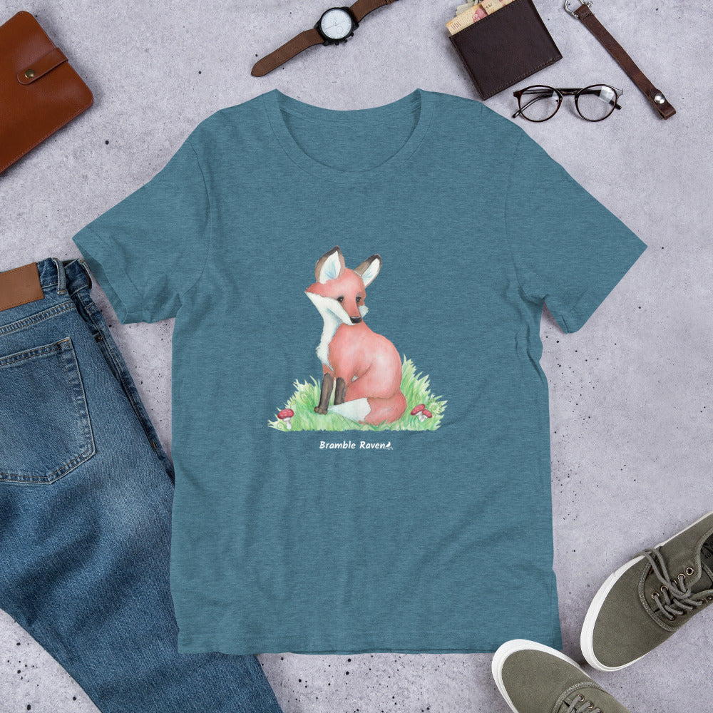 Unisex heather deep teal colored forest fox t-shirt. Features watercolor print of a fox in the grass surrounded by mushrooms and ferns.