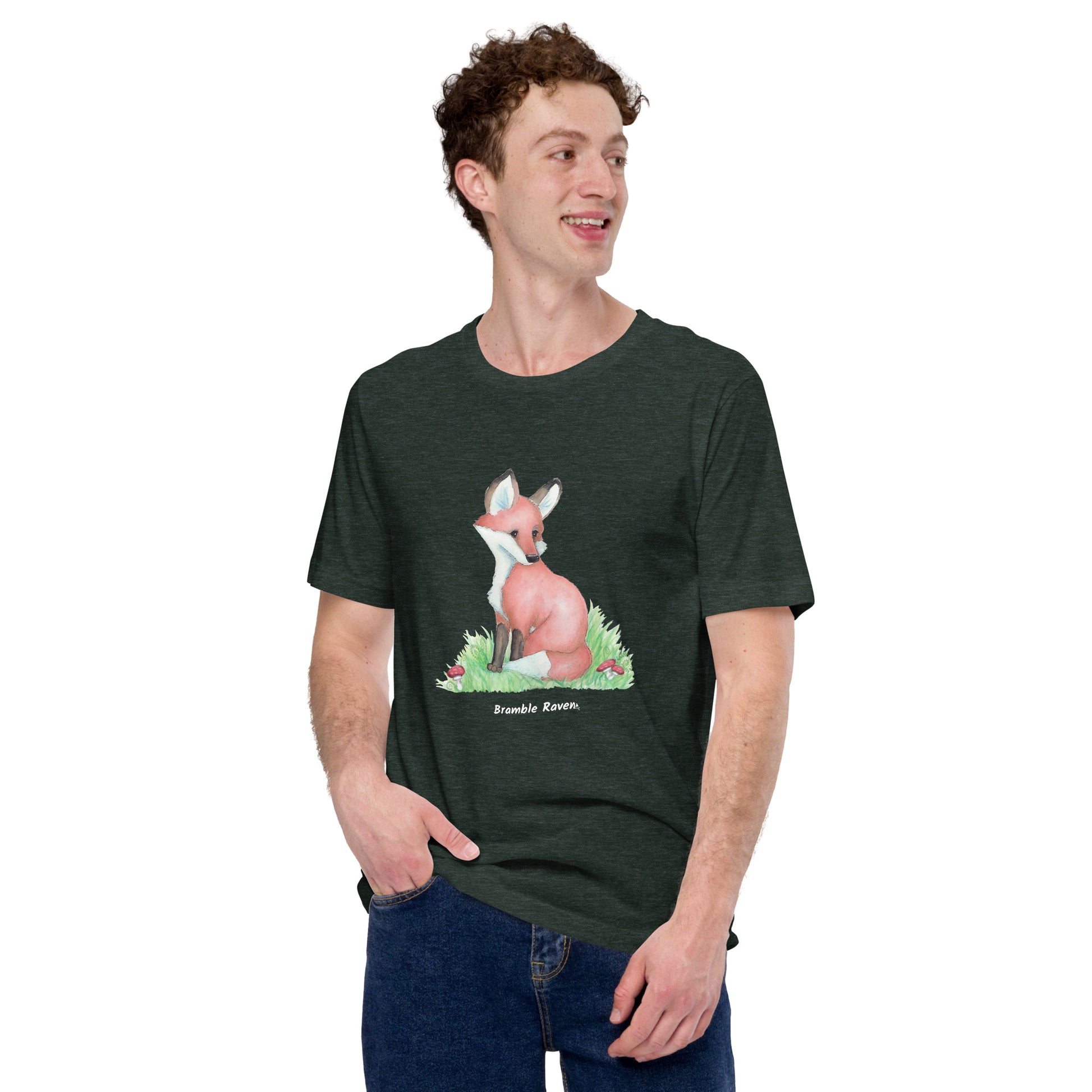 Unisex  heather forest green colored forest fox t-shirt. Features watercolor print of a fox in the grass surrounded by mushrooms and ferns. Shown on male model.