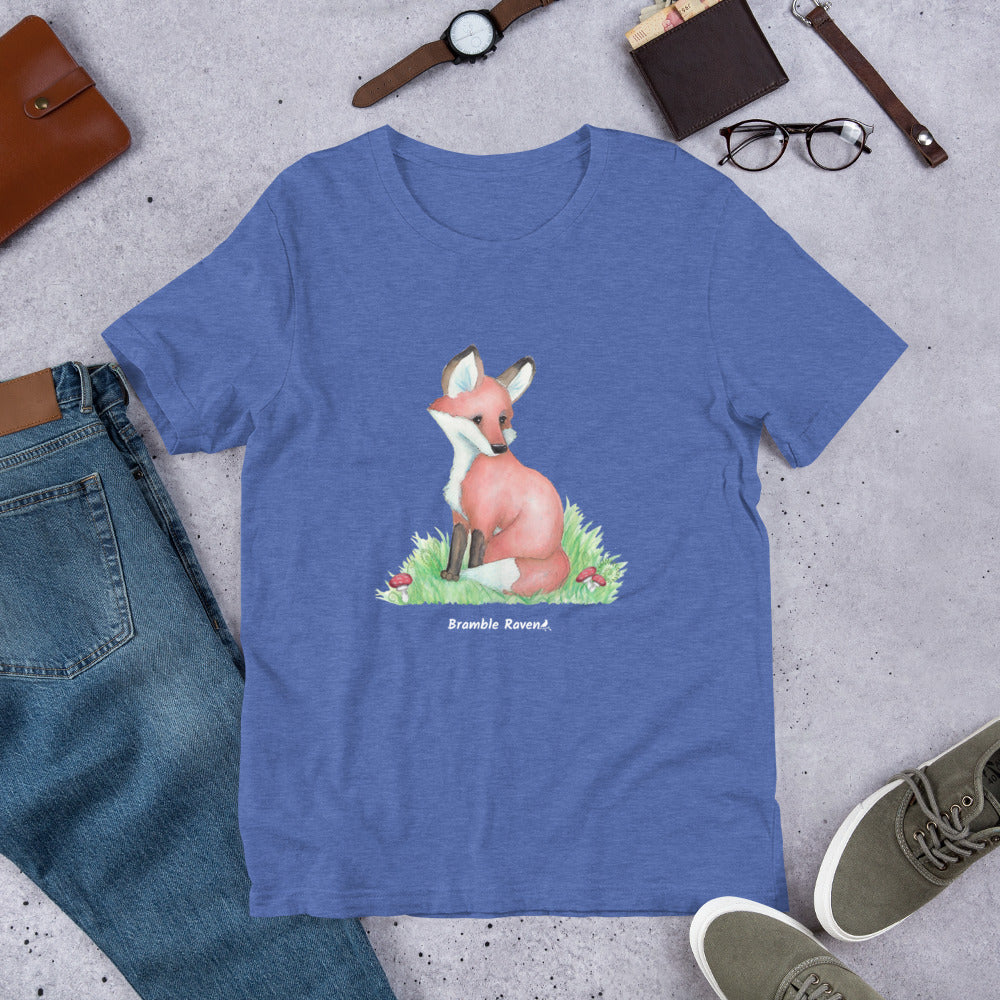 Unisex heather true royal blue colored forest fox t-shirt. Features watercolor print of a fox in the grass surrounded by mushrooms and ferns.
