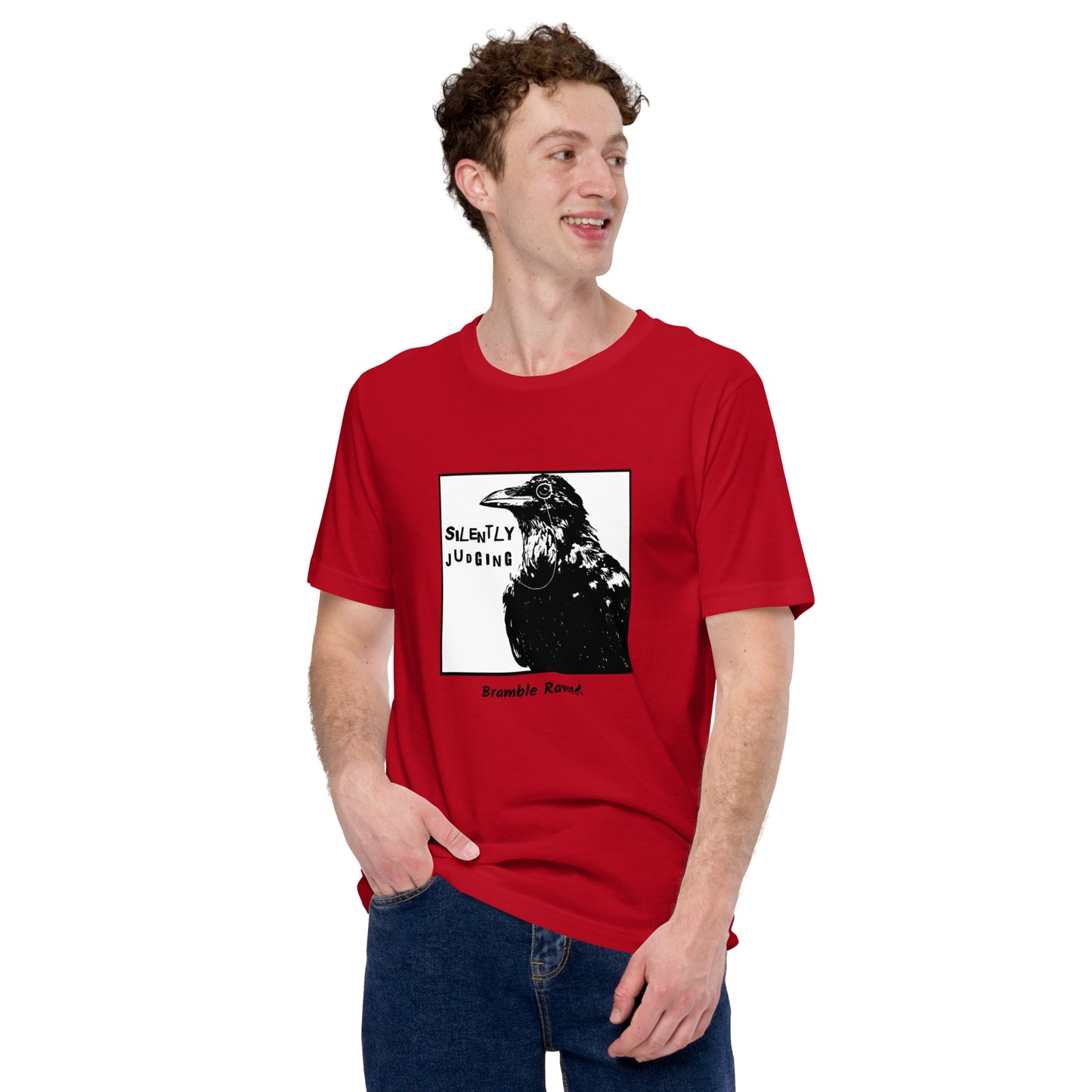 Unisex red colored t-shirt. Features silently judging text next to black crow wearing a monocle in a square frame on a white background.  Shown on male model.