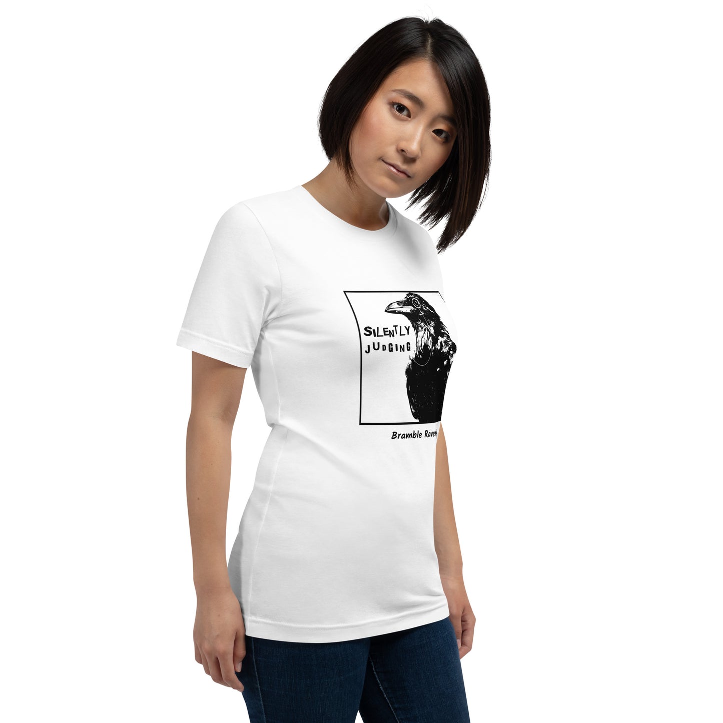 Unisex white colored t-shirt. Features silently judging text next to black crow wearing a monocle in a square frame on a white background.  Shown on female model.