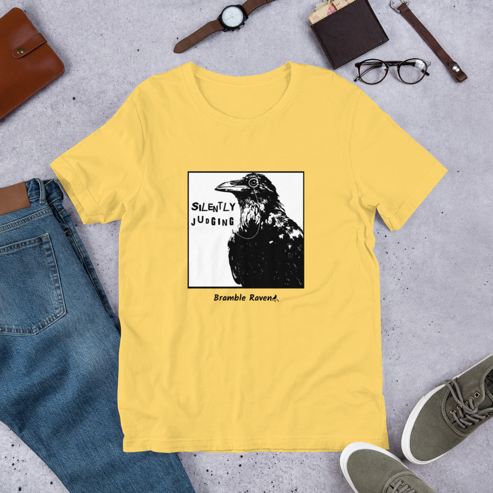 Unisex yellow colored t-shirt. Features silently judging text next to black crow wearing a monocle in a square frame on a white background. 