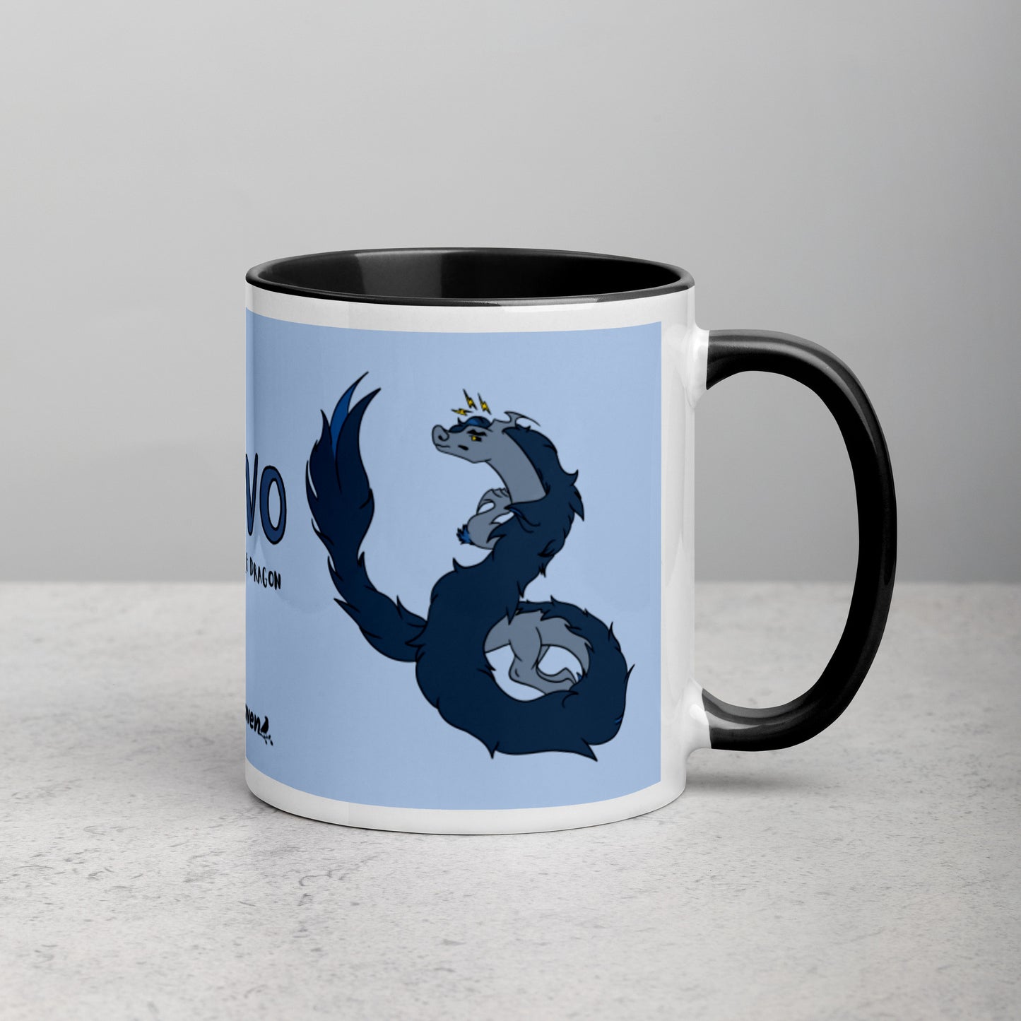 11 ounce ceramic mug featuring a double-sided image of angry Korvo the Fuzzy Noodle dragon against a light blue background.  Black inside and handle. Sitting on tabletop with handle facing right.