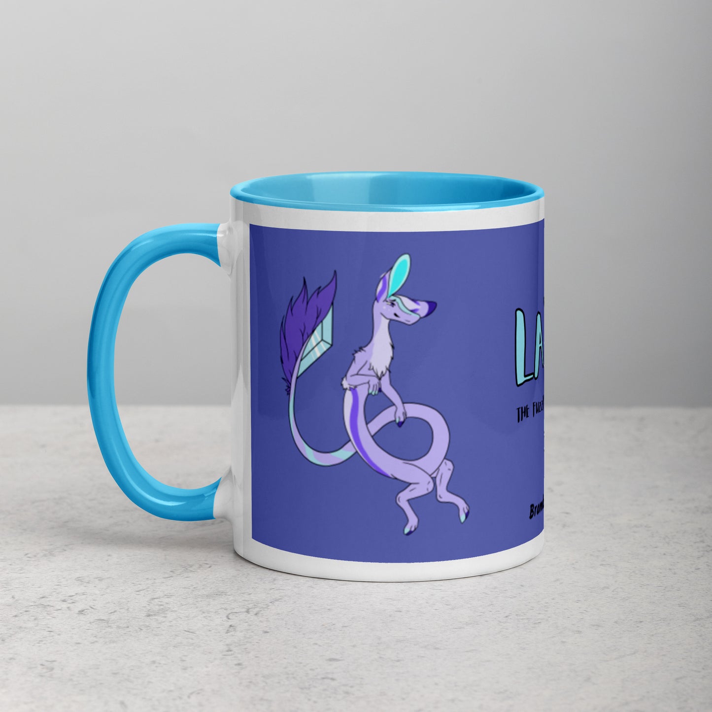 11 ounce white ceramic mug. Blue inside and handle. Features double-sided image of Layla the Lavender Fuzzy Noodle Dragon. Shown on tabletop.