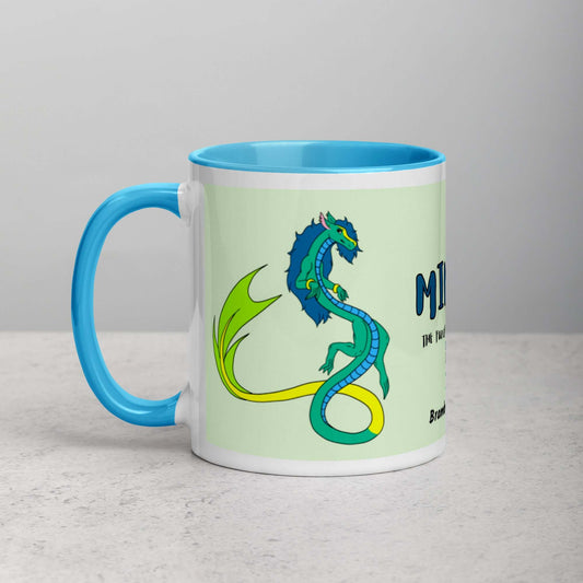 11 ounce white ceramic mug. Blue inside and handle. Features double-sided image of Mikori the Fuzzy Noodle Dragon. Shown on tabletop.
