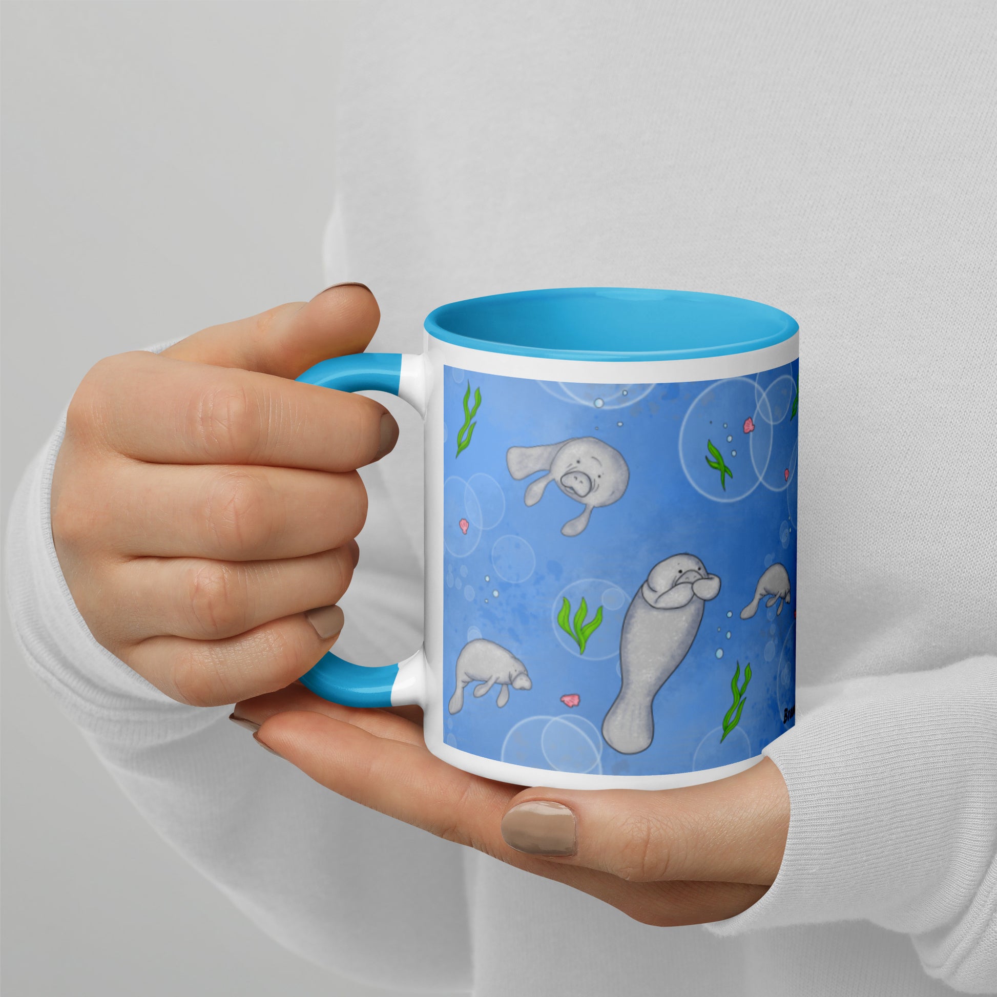 This 11 ounce mug features a wrap-around design of cute manatees, seashells, seaweed and bubbles on a blue background. Has a blue handle, rim, and inside color. This mug is microwave and dishwasher safe.