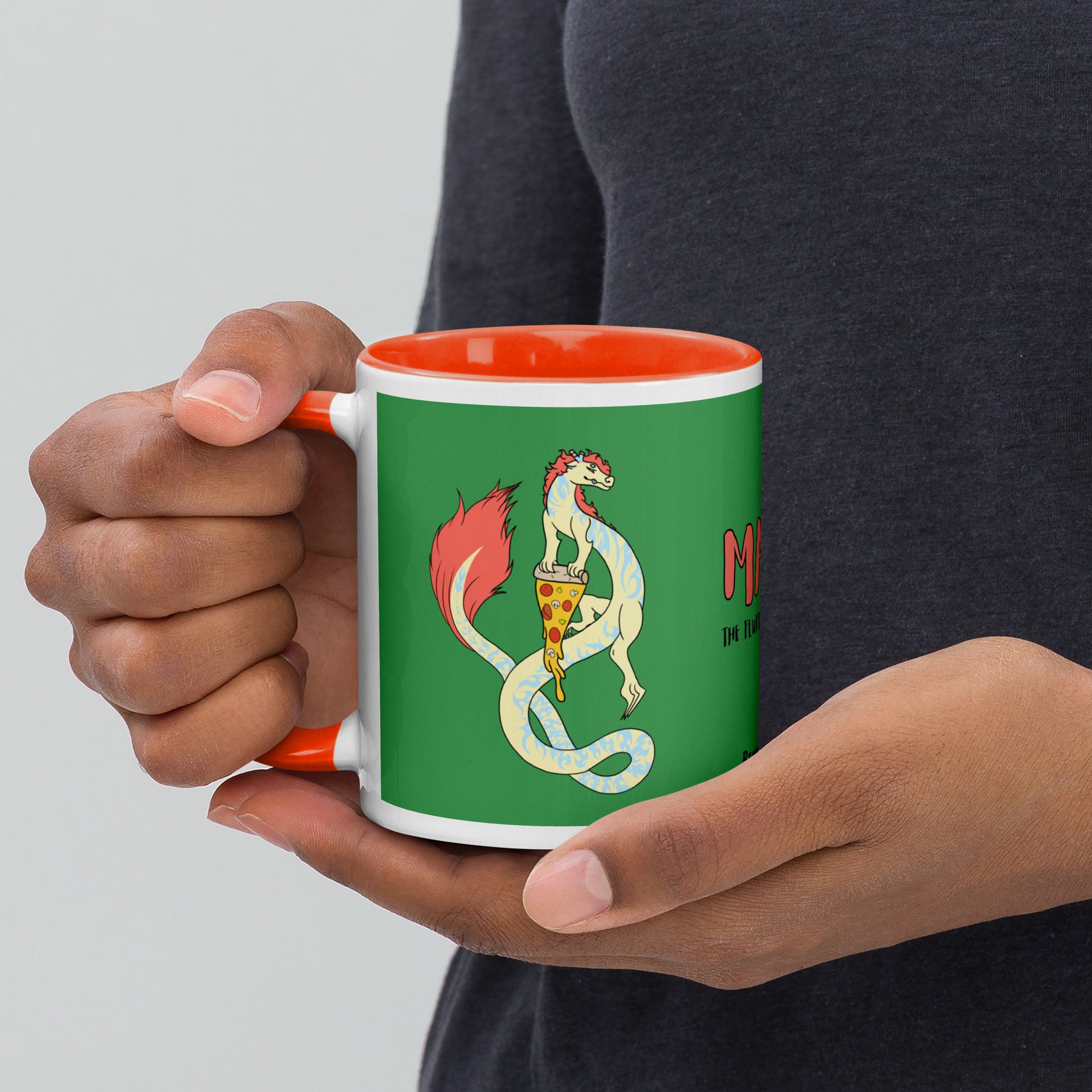 11 ounce white ceramic mug. Orange inside and handle. Features double-sided image of Maisy the Fuzzy Noodle Dragon with a slice of pizza. Shown in model's hands.