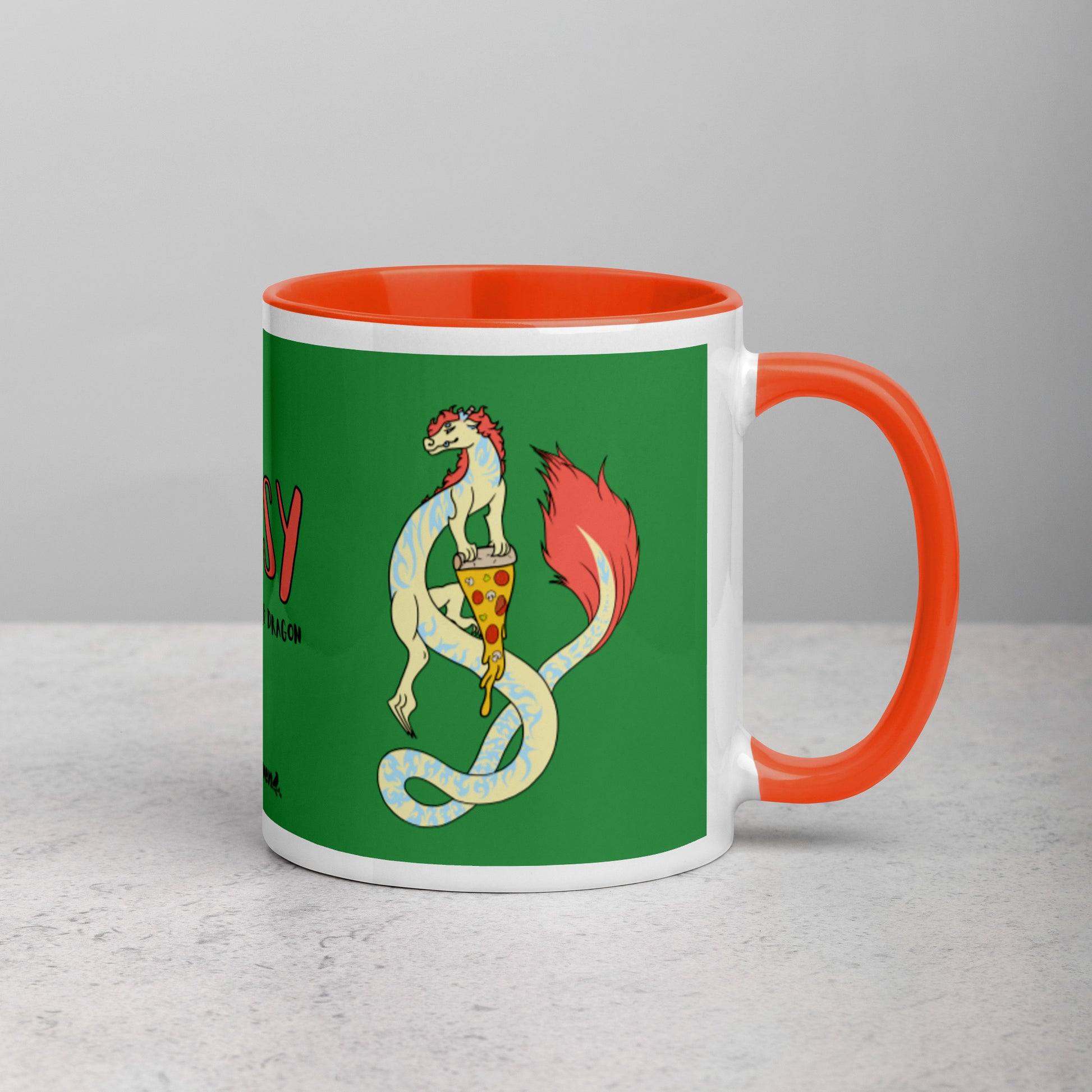 11 ounce white ceramic mug. Orange inside and handle. Features double-sided image of Maisy the Fuzzy Noodle Dragon with a slice of pizza. Shown on tabletop with handle facing right.