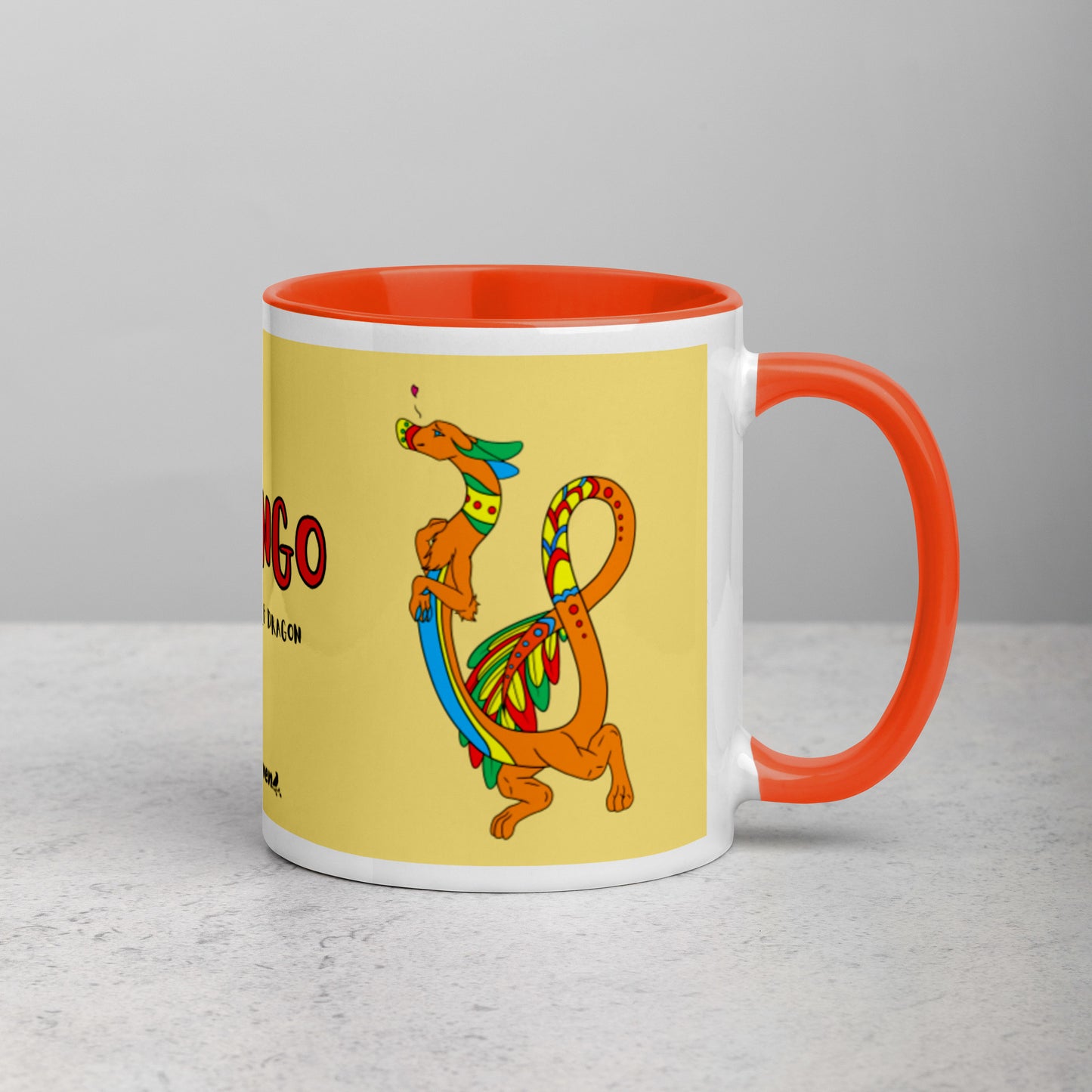 11 ounce white ceramic mug featuring a double-sided image of Domingo the Fuzzy Noodle Dragon against a light yellow background. Orange inside and handle color. Shown on tabletop with handle facing right.