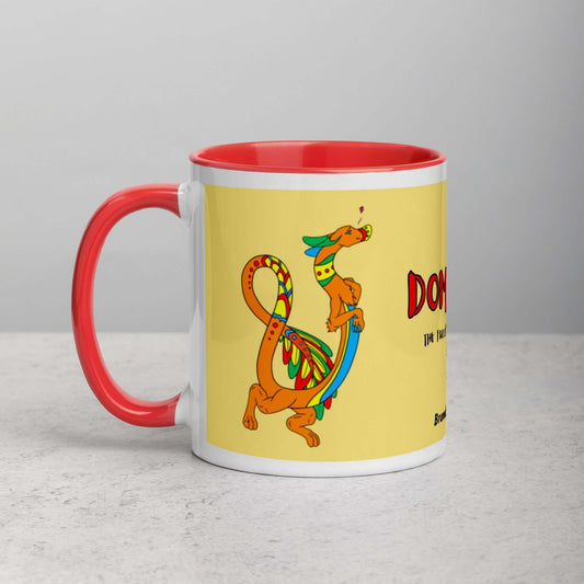 11 ounce white ceramic mug featuring a double-sided image of Domingo the Fuzzy Noodle Dragon against a light yellow background. Red inside and handle color. Shown on tabletop.