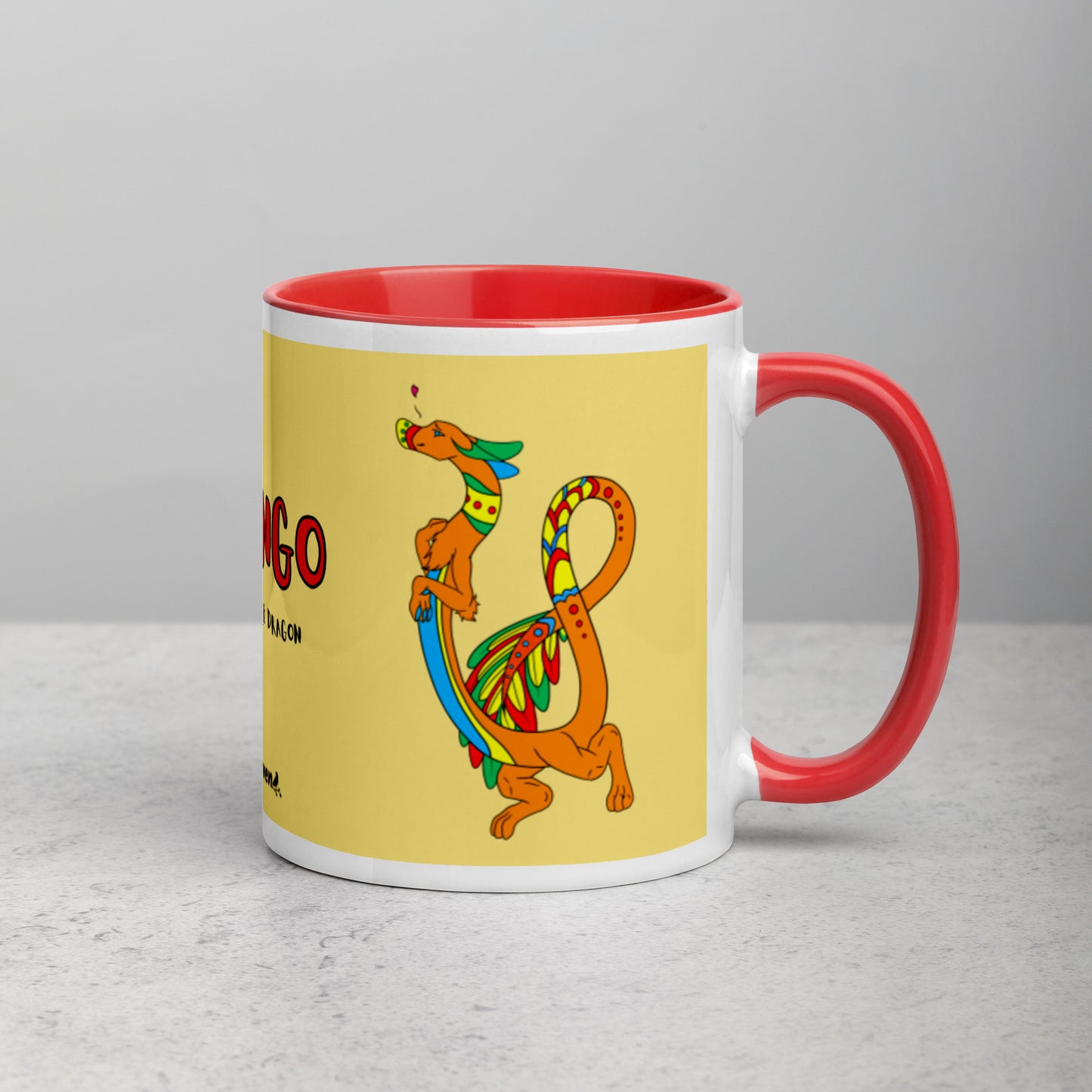 11 ounce white ceramic mug featuring a double-sided image of Domingo the Fuzzy Noodle Dragon against a light yellow background. Red inside and handle color. Shown on tabletop with handle facing right.