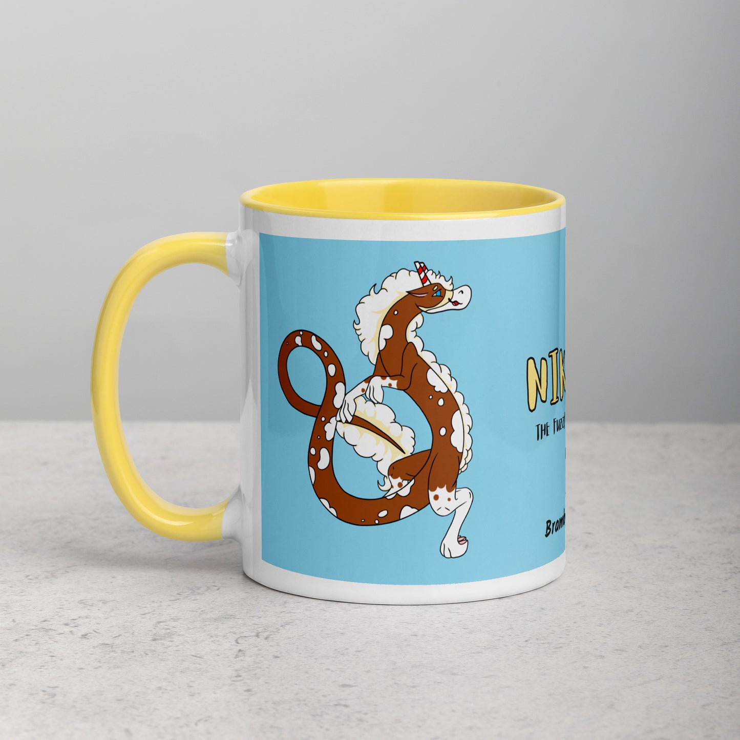 11 ounce ceramic mug with yellow handle, rim and inside color. Features double-sided image of Nikolai the Fuzzy Noodle Root beer float dragon on a light blue background. Mug is microwave and dishwasher safe.