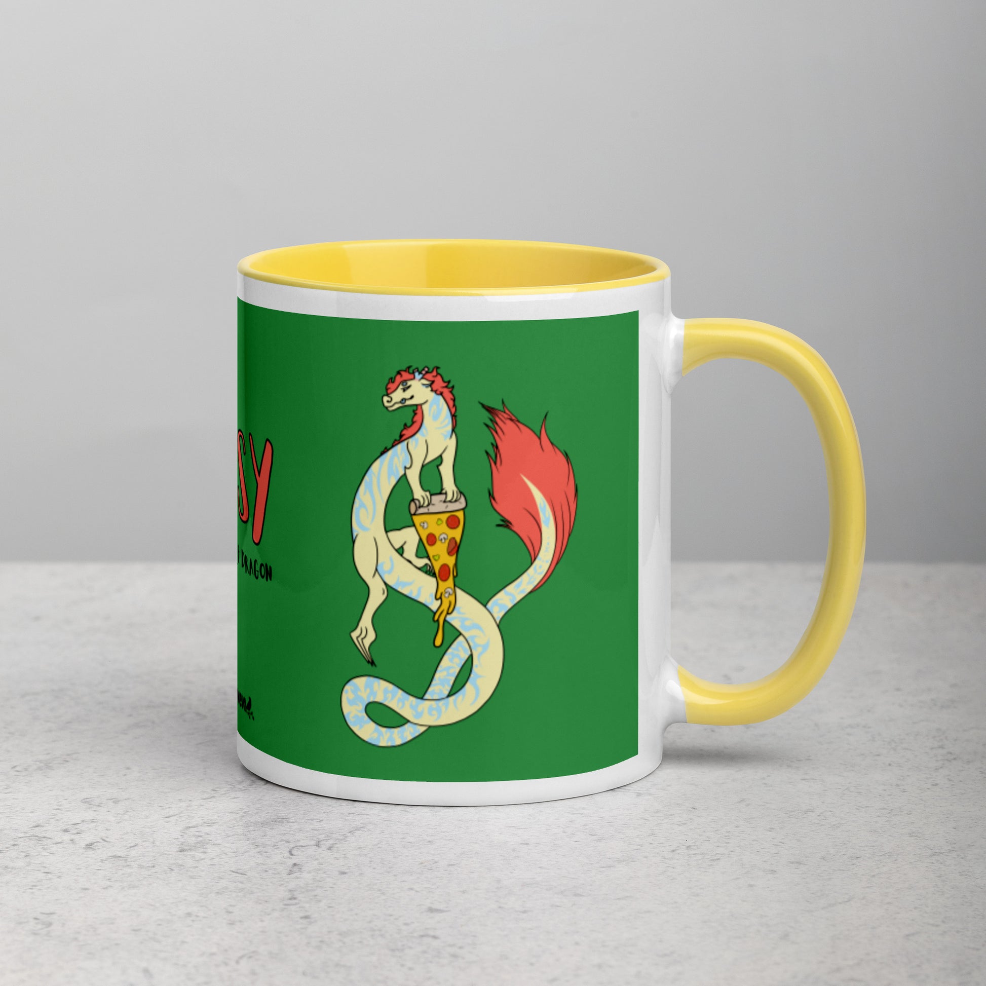 11 ounce white ceramic mug. Yellow inside and handle. Features double-sided image of Maisy the Fuzzy Noodle Dragon with a slice of pizza. Shown on tabletop.