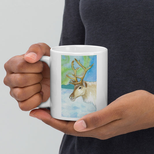 11 ounce ceramic mug featuring Northern Lights reindeer design. Double-sided print. Dishwasher and microwave safe. Shown in model's hands.